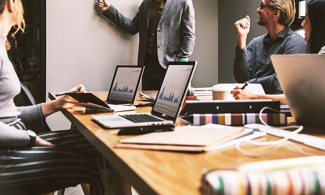 working people around a board room table looking at a presenter