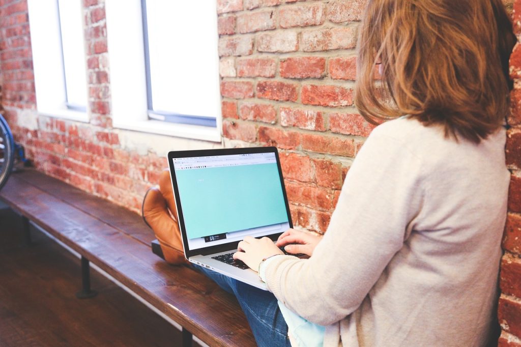 woman sat on a window seat with a laptop on her lap depicting flexible working