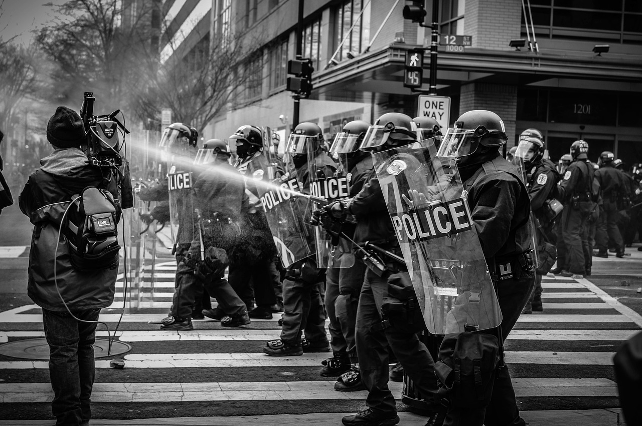 Police in riot gear holding back rioters